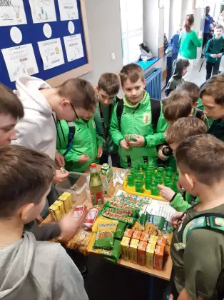 Uczniowie stoją wokół stołu na którym rozłożone są zielone produkty spożywcze