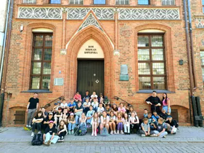 Uczniowie z nauczycielami i przewodnikiem, w tle dom Mikołaja Kopernika