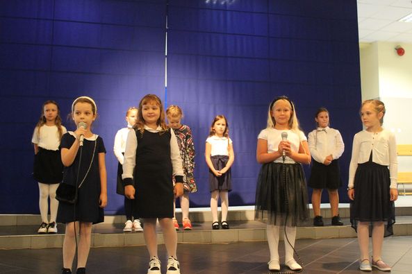 granatowa ściana, dziewczynki stoją, mikrofon, biała koszula