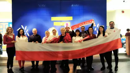 Grupa nauczycieli ubrana w stroje w barwach narodowych trzymająca polską flagę