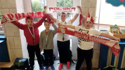 Grupa uczniw trzymajca szaliki w barwach narodowych
